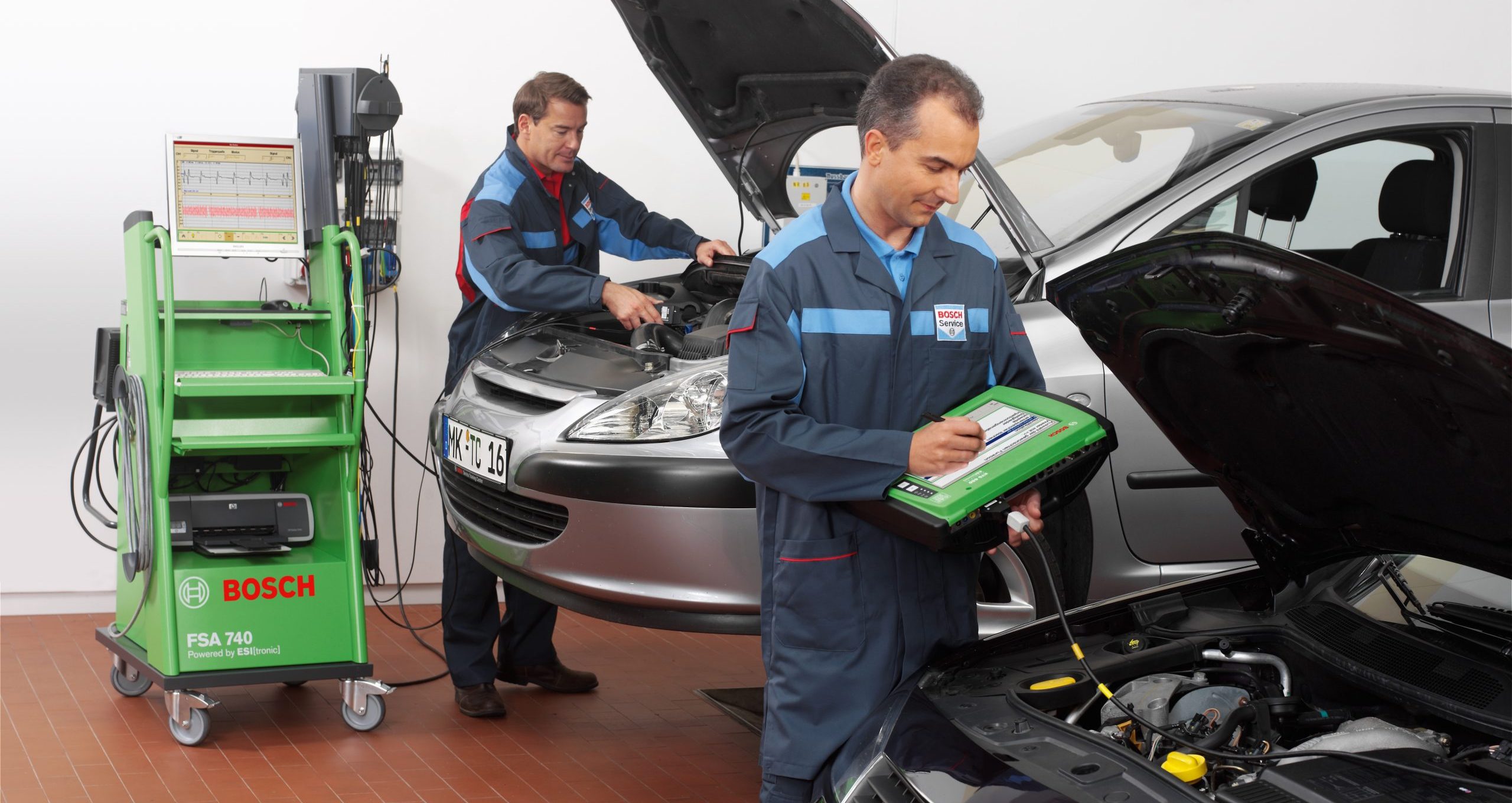 KFZ-Mechatroniker schließt Diagnose im Motorraum des Autos an.